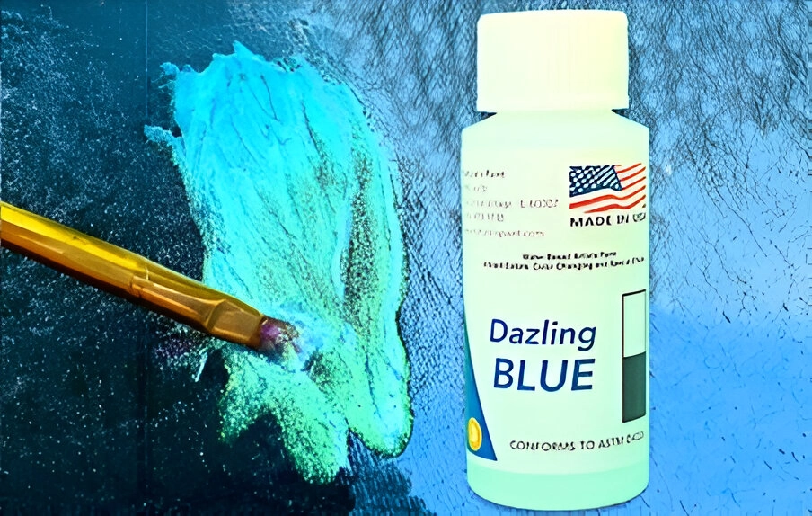 A paintbrush applies blue paint next to a white bottle labeled "Dazling Blue" with an American flag and text indicating it is made in the USA.