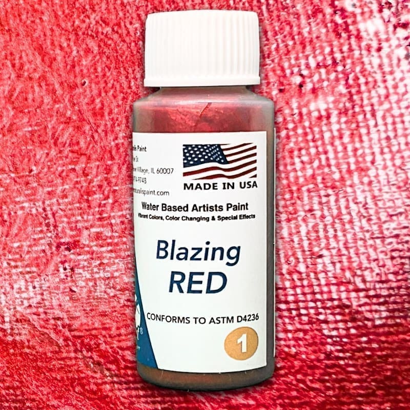 A bottle of Blazing Red water-based artists paint, featuring a textured red background and a label with the American flag, "Made in USA," and compliance with ASTM D4236.