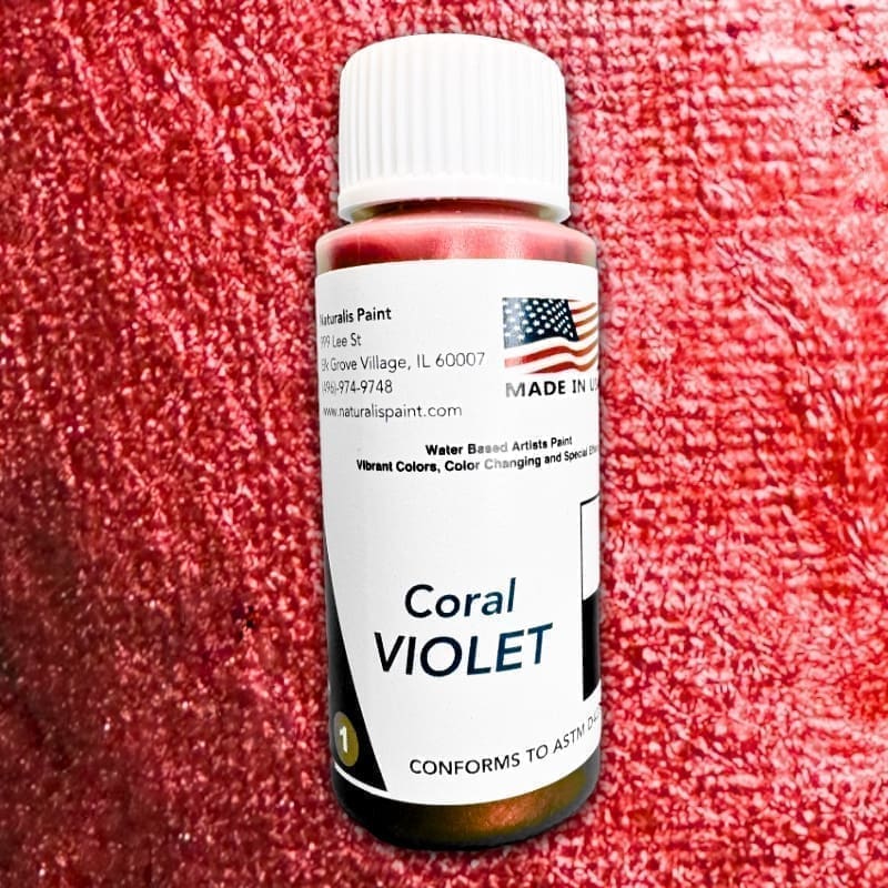 A small bottle of water-based artistic paint named "Coral Violet," featuring a label with an American flag and contact information for Naturalis Paint, located in Elk Grove Village, IL.