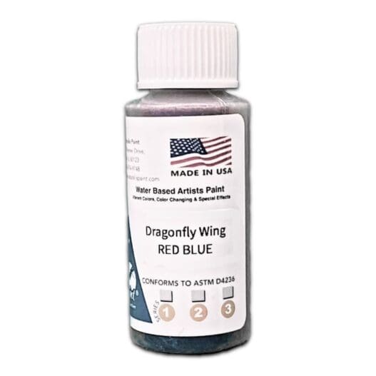 A white, cylindrical bottle labeled "Dragon Fly Wing Red Blue" with "Made in USA" text and an American flag. It contains water-based artist paint designed for special effects and conforms to ASTM D4236 standards.