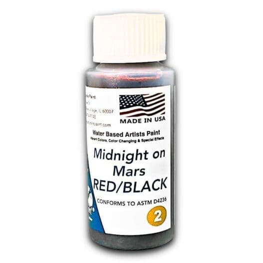 A small bottle of water-based artist paint labeled "Midnight on Mars Red Black" features an American flag, product details, and a compliance statement with ASTM D4236.