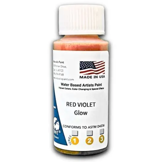 A small bottle labeled "Red Violet Glow" water-based artist paint, featuring an American flag and the text "Made in USA." The label also indicates it conforms to ASTM D4236 standards.